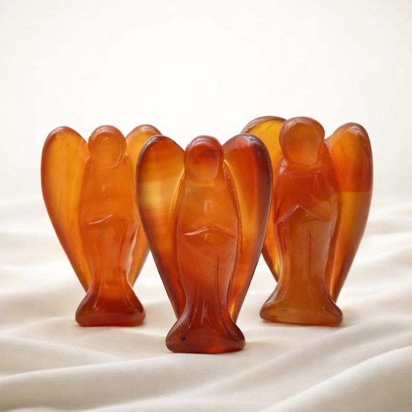 Symbolbild Sternzeichen Widder mit drei roten Engeln aus Karneol auf hellem Stoffhintergrund.