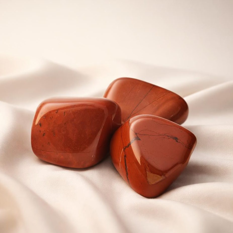 Roter Jaspis Trommelsteine auf hellem Stoffhintergrund als Edelstein-Klassiker.