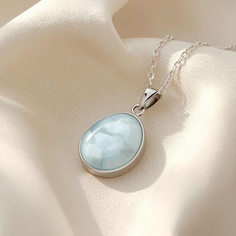 Larimar Anhänger mit Silberfassung und Kette auf hellem Stoffhintergrund – Symbolbild für Edelsteine und Aszendent Schütze.