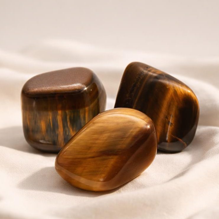 Tigerauge Trommelsteine auf hellem Stoffhintergrund – Symbolbild für die Chinesische Sternzeichen Zuordnung.