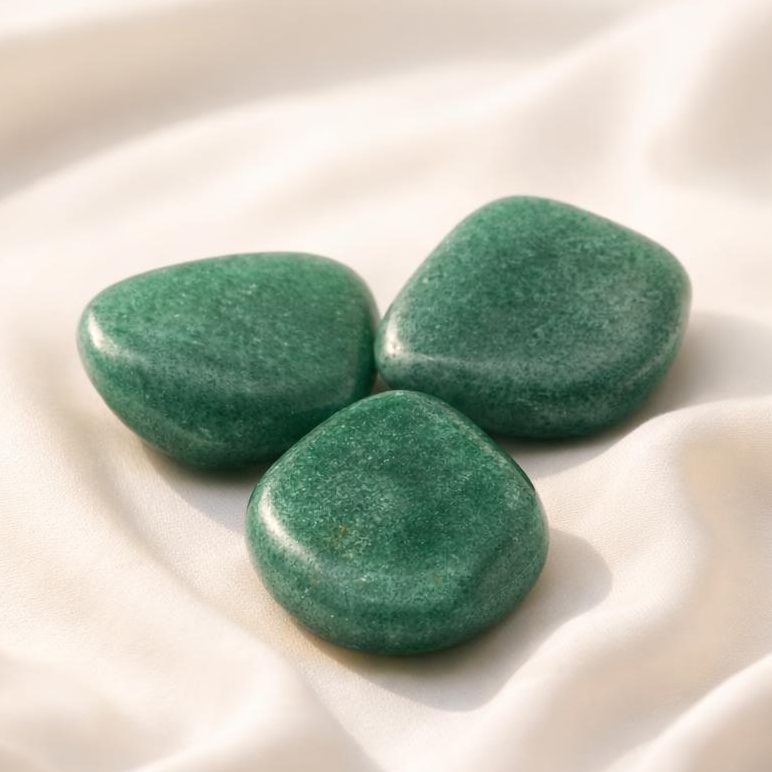 Grüner Aventurin Trommelsteine auf hellem Stoffhintergrund als Edelstein-Klassiker.