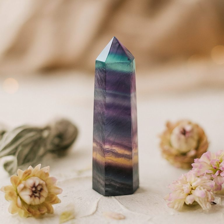 Fluoritspitze – Edelstein mit Ausdruck und Geschichte Fluoritspitze mit Blüten – stimmungsvolles Stillleben in sanften Naturtönen, Symbol für die Themenwelten von Sandras Mineralien.