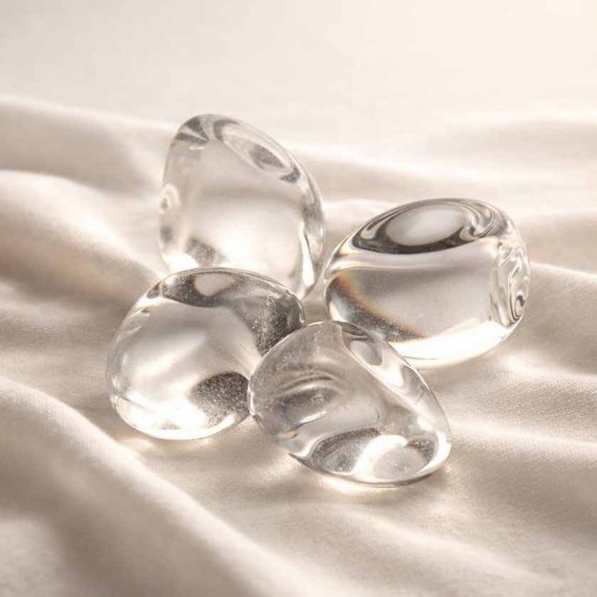 Bergkristall Trommelsteine auf hellem Stoffhintergrund als Edelstein-Klassiker.